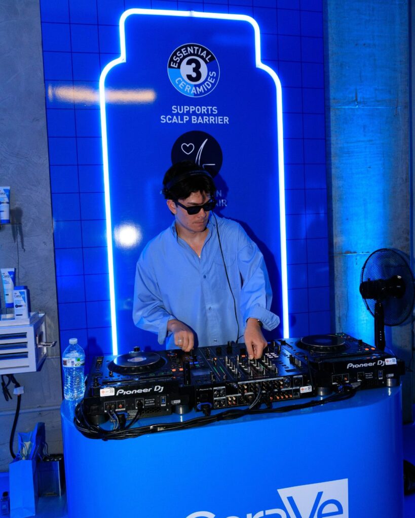 DJ performing at a CeraVe brand activation with neon bottle backdrop